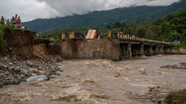 Warga menyaksikan jembatan yang putus akibat tergerus banjir di Desa Pakuli, Gumbasa, Sigi, Sulawesi Tengah, Selasa (6/9/2022). [ANTARA FOTO/Basri Marzuki/tom]