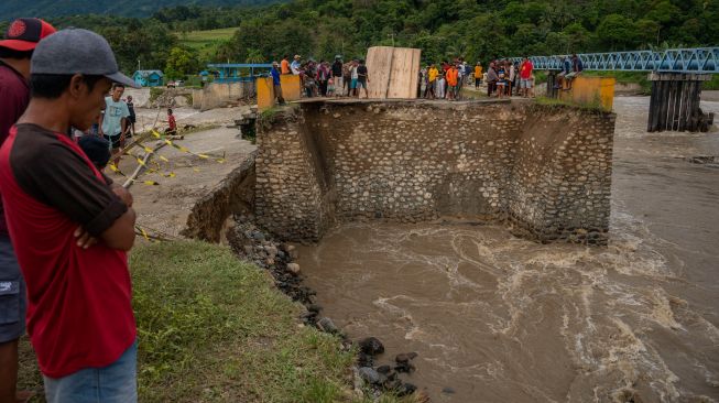 Warga menyaksikan jembatan yang putus akibat tergerus banjir di Desa Pakuli, Gumbasa, Sigi, Sulawesi Tengah, Selasa (6/9/2022). [ANTARA FOTO/Basri Marzuki/tom]