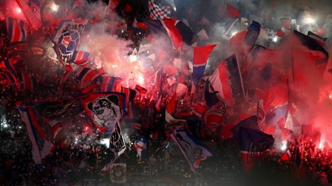 Pendukung Paris Saint-Germain (PSG) mengibarkan bendera dan suar cahaya selama matchday pertama Grup H Liga Champions UEFA antara PSG vs Juventus di Stadion Parc des Princes di Paris, pada 6 September 2022.
Anne-Christine POUJOULAT / AFP.