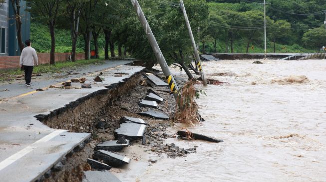 Seorang pria berjalan di sepanjang jalan yang rusak akibat Topan Hinnamnor di Gyeongju, Korea Selatan, Selasa (6/9/2022). [YONHAP/AFP]