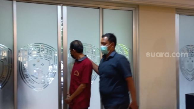 Penampakan S tersangka kasus pencabulan anak saat mengenakan baju tahanan di Polda Metro Jaya. (Suara.com/M Yasir)