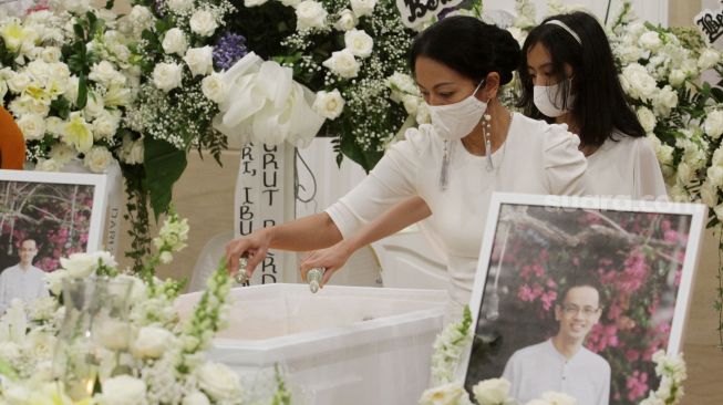 Dewi lestari menyiramkan air suci ke peti jenazah suaminya Reza Gunawan, di Rumah Duka Grand Heaven, Jakarta, Kamis (8/9). [Suara.com/Oke Atmaja]