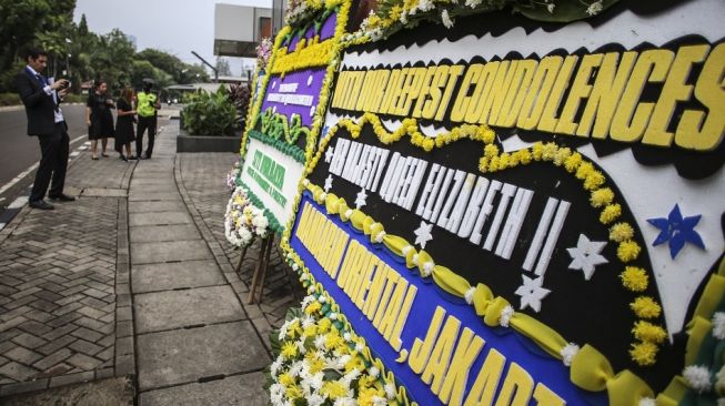 Staf kedutaan memotret karangan bunga bela sungkawa atas wafatnya Ratu Elizabeth II di Kedutaan Besar Inggris, Jakarta, Jumat (9/9/2022). (ANTARA FOTO/Rivan Awal Lingga/rwa).