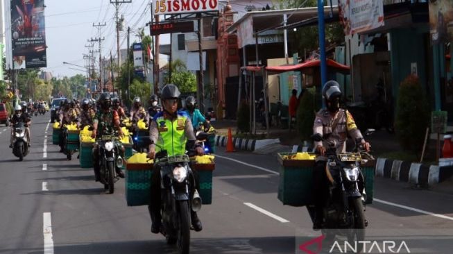 Kepala Polres Sukoharjo AKBP Wahyu Nugroho Setyawan (depan kiri) memimpin pembagian sembako dengan motor  bronjong di Jalan Jenderal Soedirman Sukoharjo, Jumat (9/9/2022) [ANTARA/Bambang Dwi Marwoto].