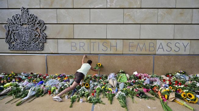 Seorang warga meletakkan bunga di depan Kedutaan Besar Inggris untuk memberikan penghormatan kepada Ratu Elizabeth II di Berlin, Jerman, Jumat (9/9/2022). [John MACDOUGALL / AFP]