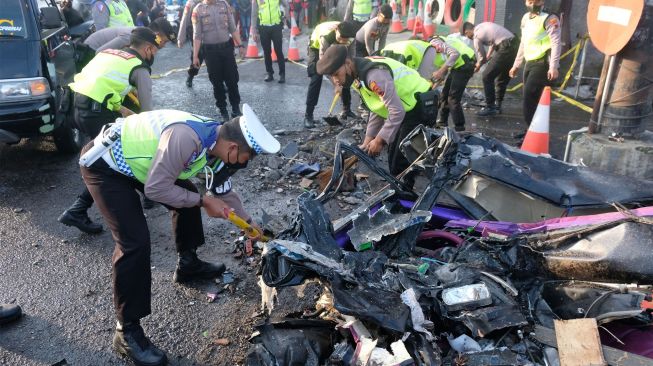 Polisi membersihkan puing-puing mobil pikap yang ringsek di lokasi kecelakaan maut jalan raya Parakan-Wonosobo Kertek, Wonosobo, Jawa Tengah, Sabtu (10/9/2022). [ANTARA FOTO/Anis Efizudin/nym]