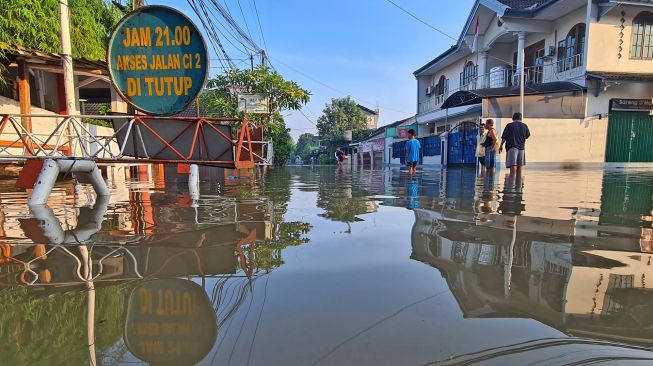 Sejumlah warga melintasi banjir yang merendam Perumahan Ciledug Indah, Ciledug, Tangerang, Banten, Minggu (11/9/2022). [ANTARA FOTO/Muhammad Iqbal/YU]