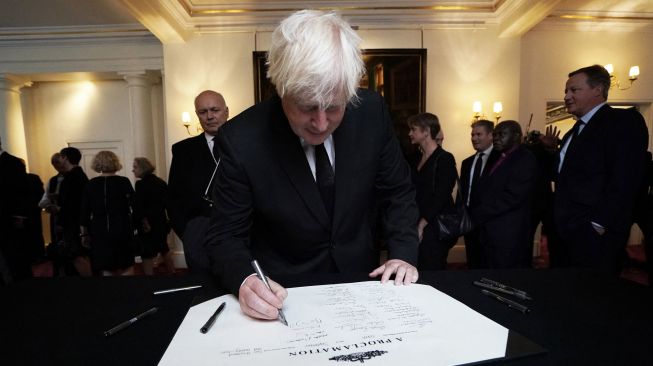 PeMantan Perdana Menteri Inggris Boris Johnson saat menandatangani Proklamasi Aksesi Raja Charles III saat pertemuan Dewan Aksesi di dalam Istana St James di London, Inggris, Sabtu (10/9/2022). [Kirsty O'Connor / POOL / AFP]