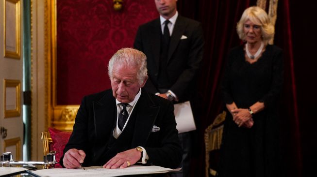 Raja Inggris Charles III saat menandatangani sumpah bahwa ia akan menegakkan keamana terhadap Gereja di Skotlandia, saat pertemuan Dewan Aksesi yang memproklamirkannya dirinya Raja baru di dalam Istana St James di London, Inggris, Sabtu (10/9/2022). [Victoria Jones / POOL / AFP]