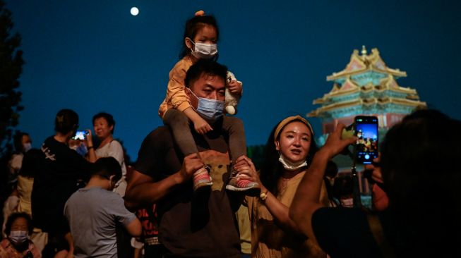 Sebuah keluarga berswafoto saat menghadiri Festival Pertengahan Musim Gugur di Beijing, China, Sabtu (10/9/2022). [Jade Gao / AFP]
