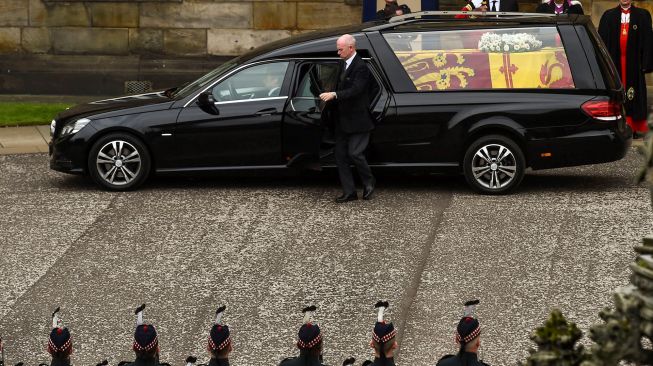 Mobil jenazah yang membawa peti mati mendiang Ratu Elizabeth II saat tiba di Istana Holyroodhouse, Edinburgh, Skotlandia, Minggu (11/9/2022). [Lisa Ferguson / POOL / AFP]