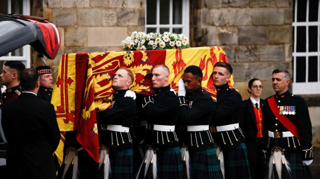 Petugas membawa peti jenazah mendiang Ratu Elizabeth II Inggris yang ditutupi dengan bendera Royal Standard of Scotland saat tiba di Istana Holyroodhouse, Edinburgh, Skotlandia, Minggu (11/9/2022).[ALKIS KONSTANTINIDIS / POOL / AFP]