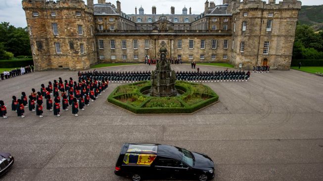 Mobil jenazah yang membawa peti mati mendiang Ratu Elizabeth II saat tiba di Istana Holyroodhouse, Edinburgh, Skotlandia, Minggu (11/9/2022). [Lisa Ferguson / POOL / AFP]