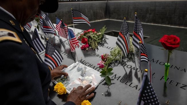 Kolonel Davis menyentuh foto rekannya Kapten Micheal Dermott Mullan yang tewas saat Peringatan 9/11 di New York, Amerika Serikat, Minggu (11/9/2022). [Yuki IWAMURA / AFP]
