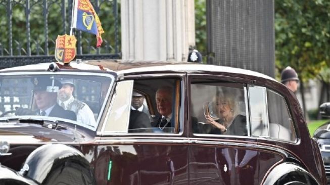 Raja Charles III dan Permaisuri Camilla bertolak dari Palace of Westminster setelah pidato di Houses of Parliament, Westminster Hall, London (12/9/2022) setelah Ratu Elizabeth II mangkat pada 8 September [AFP/Marco Bertorello].