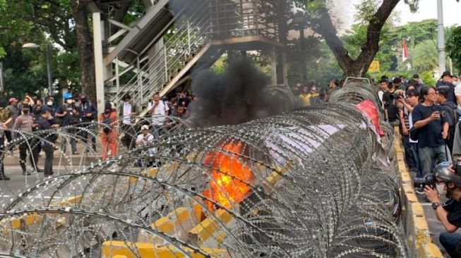 Massa aksi membakar ban saat berunjuk rasa menolak kenaikan harga BBM di kawasan Patung Kuda Arjuna Wiwaha, Jakarta pada Selasa (13/9/2022). [Suara.com/Rakha]