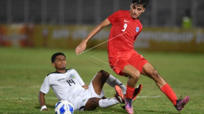 Pesepak bola Singapura U19 Ilyasin Zayan (kanan) berebut bola dengan pesepak bola Timor Leste U19 Sandro Lima Quintao (kiri) dalam laga penyisihan grup Piala AFF U19 di Stadion Madya Senayan, Jakarta, Selasa (5/7/2022). ANTARA FOTO/Akbar Nugroho Gumay