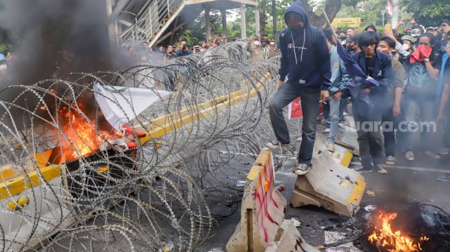 Massa aliansi mahasiswa, pelajar dan sejumlah elemen buruh mencoba merubuhkan kawat duri saat melakukan aksi unjuk rasa menolak kenaikan harga BBM di kawasan Patung Kuda, Jakarta Pusat, Selasa (13/9/2022). [Suara.com/Alfian Winanto]