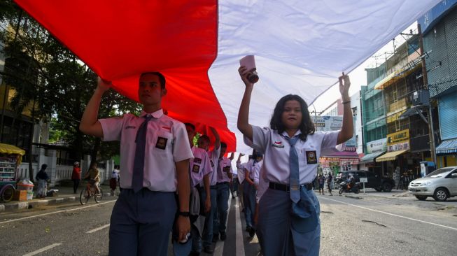 Sejumlah peserta membentangkan bendera merah putih di kawasan Jalan Brigjend Katamso, Medan, Sumatera Utara, Selasa (13/9/2022). [ANTARA FOTO/Fransisco Carolio/Ief/aww]