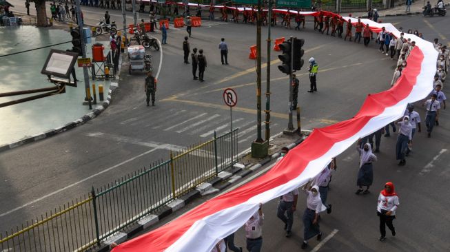 Sejumlah peserta membentangkan bendera merah putih di kawasan Jalan Brigjend Katamso, Medan, Sumatera Utara, Selasa (13/9/2022). [ANTARA FOTO/Fransisco Carolio/Ief/aww]