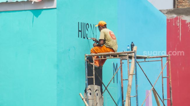 Sejumlah petugas Penanganan Prasarana & Sarana Umum (PPSU) menyelesaikan pembuatan mural di Kampung Gembira Gembrong, Jakarta Timur, Rabu (14/9/2022). [Suara.com/Alfian Winanto]