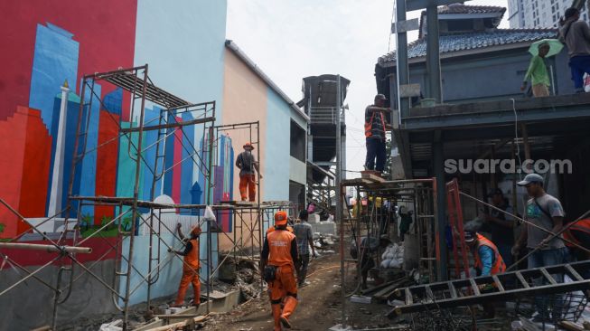 Sejumlah petugas Penanganan Prasarana & Sarana Umum (PPSU) menyelesaikan pembuatan mural di Kampung Gembira Gembrong, Jakarta Timur, Rabu (14/9/2022). [Suara.com/Alfian Winanto]