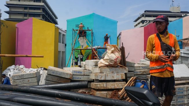 Sejumlah petugas Penanganan Prasarana & Sarana Umum (PPSU) menyelesaikan pembuatan mural di Kampung Gembira Gembrong, Jakarta Timur, Rabu (14/9/2022). [Suara.com/Alfian Winanto]