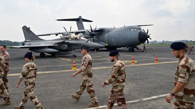 Personel Angkatan Udara Prancis berjalan melewati pesawat tempur Multirole Dassault Rafale (kiri) dan pesawat angkut Airbus A-400M (kanan) untuk demonstrasi penerbangan di pangkalan udara Halim Perdanakusuma di Jakarta, Indonesia, Selasa (12/9/2022). [ADEK BERRY / AFP]
