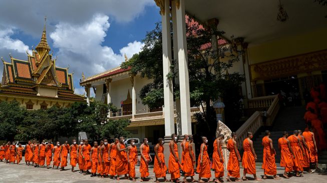 Para Biksu mengantre untuk makan siang selama festival Pchum Ben (Festival Kematian) di sebuah pagoda di Phnom Penh, Kamboja, Selasa (13/9/2022). [TANG CHHIN Sothy / AFP]