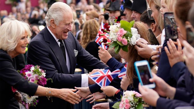 Raja Inggris Charles III dan Permaisuri Camilla menyapa masyarakat saat tiba di Kastil Hillsborough, Belfast, Irlandia Utara, Selasa (13/9/2022). [Niall Carson / POOL / AFP]