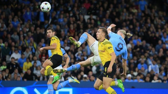 Striker Manchester City asal Norwegia Erling Haaland (tengah) melepaskan tembakkan spektakuler untuk membobol gawang Borussia Dortmund dalam matchday kedua Grup G Champions League (Liga Champions) 2022-2023 antara Man City vs Dortmund di Stadion Etihad, Manchester pada Kamis (15/9/2022) dini hari WIB. Man City menang 2-1. Lindsey Parnaby / AFP.