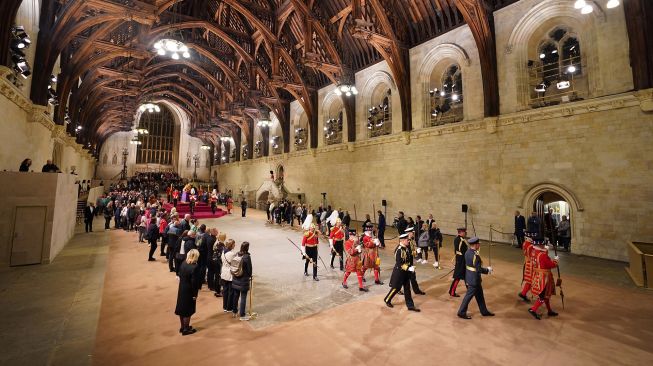 Orang-orang memberikan penghormatan di dekat peti mati mendiang Ratu Elizabeth II, yang terbaring di catafalque di Westminster Hall di Istana Westminster di London, Inggris, Jumat (16/9/2022). [AFP Photo]

