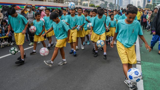 Sejumlah anak bermain bola saat parade perkenalan maskot Piala Dunia U-20 2023 pada Hari Bebas Kendaraan Bermotor atau Car Free Day (CFD) di kawasan Bunderan Hotel Indonesia, Jakarta, Minggu (18/9/2022). [ANTARA FOTO/Galih Pradipta/tom]