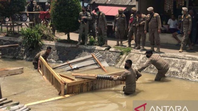 Satpol PP Kabupaten Bekasi bongkar bangunan liar yang berdiri di atas lahan irigasi Kampung Gandaria, Desa Cibarusah Kota, Kecamatan Cibarusah. [Antara]