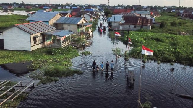 Foto udara sejumlah warga melintasi di permukiman sekitar rumahnya yang terendam banjir di Jalan Anoi Ujung, Palangka Raya, Kalimantan Tengah, Sabtu (17/9/2022). [ANTARA FOTO/Makna Zaezar/aww]