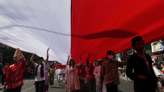 Warga membentangkan kain berwarna Merah Putih dengan panjang 770 meter pada peringatan peristiwa perobekan bendera Belanda oleh pejuang di Hotel Majapahit (dulu Hotel Yamato) Jalan Tunjungan, Surabaya, Jawa Timur, Minggu (18/9/2022). [ANTARA FOTO/Didik Suhartono/tom]