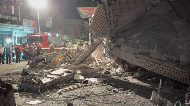 Pegawai pemerintah memeriksa lokasi sebuah gedung yang runtuh akibat gempa bumi di Hualien, Taiwan, Minggu (18/9/2022). [Sam Yeh / AFP]