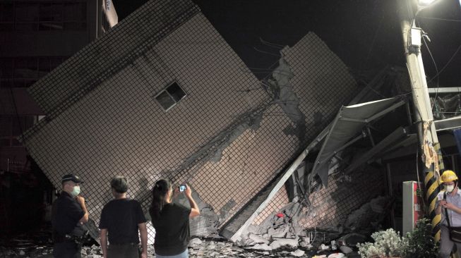 Pegawai pemerintah memeriksa lokasi sebuah gedung yang runtuh akibat gempa bumi di Hualien, Taiwan, Minggu (18/9/2022). [Sam Yeh / AFP]