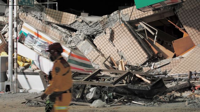 Petugas penyelamat melewati gedung yang runtuh akibat gempa bumi yang mengguncang di Hualien, Taiwan, Minggu (18/9/2022). [Sam Yeh / AFP]