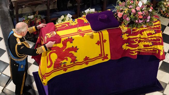 Raja Charles III menempatkan Queen's Company Camp Color of the Grenadier Guards di atas peti mati saat prosesi pemakaman Ratu Inggris Elizabeth II di Kapel St George yang ada di dalam Kastil Windsor, Inggris, Senin (19/9/2022).  [Jonathan Brady / POOL / AFP]
