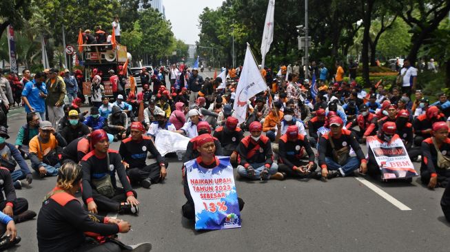 Sejumlah buruh duduk menutup Jalan Medan Merdeka Selatan saat berunjuk rasa di depan Balai Kota DKI Jakarta, Jakarta, Rabu (21/9/2022). [ANTARA FOTO/Aditya Pradana Putra/nz].