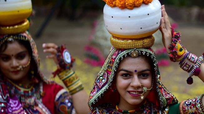 Peserta dari kelompok seni yang mengenakan pakaian tradisional berpose saat latihan tari Garba menjelang festival Navratri di Ahmedabad, India, Selasa (20/9/2022). [SAM PANTHAKY / AFP]