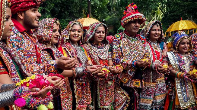 Peserta dari kelompok seni yang mengenakan pakaian tradisional berpose saat latihan tari Garba menjelang festival Navratri di Ahmedabad, India, Selasa (20/9/2022). [SAM PANTHAKY / AFP]