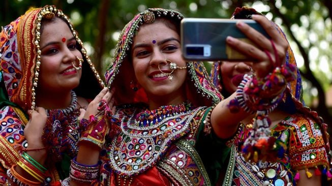 Peserta dari kelompok seni yang mengenakan pakaian tradisional berpose saat latihan tari Garba menjelang festival Navratri di Ahmedabad, India, Selasa (20/9/2022). [SAM PANTHAKY / AFP]