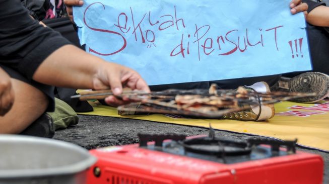 Massa dari Forum Masyarakat Peduli Pendidikan Jawa Barat memasak ikan asin saat aksi tolak mahalnya biaya sekolah di Gedung DPRD Jabar, Bandung, Jawa Barat, Kamis (22/9/2022). [ANTARA FOTO/Raisan Al Farisi/rwa].