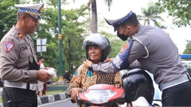 Petugas memasangkan helm baru kepada seorang pengendara usai memberikan edukasi tertib berlalu lintas di Jalan Udayana, Mataram, NTB, Rabu (21/9/2022) [ANTARA/Dhimas BP].