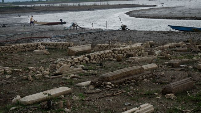 Warga berusaha mengalirkan air di area pemakaman lama di Waduk Gajah Mungkur yang mengalami penyusutan air di Wuryantoro, Kabupaten Wonogiri, Jawa Tengah, Rabu (21/9/2022). ANTARA FOTO/Maulana Surya