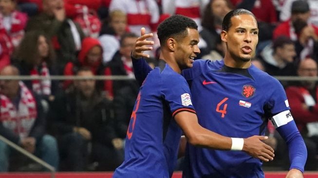 Penyerang Timnas Belanda Cody Gakpo (kiri) diberi selamat oleh Virgil van Dijk setelah mencetak gol pertama timnya dalam matchday kelima Liga A Grup 3 UEFA Nations League 2022-2023 antara Polandia vs Belanda di Warsawa, Polandia pada 22 September 2022.JANEK SKARZYNSKI / AFP.