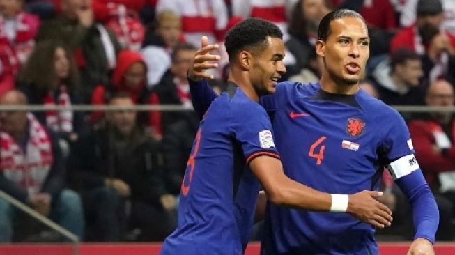 Pemain depan Belanda Cody Gakpo (kiri) mendapatkan selamat dari bek Belanda Virgil van Dijk setelah mencetak gol pertama tim selama pertandingan sepak bola Grup 4 Liga Bangsa-Bangsa UEFA antara Polandia dan Belanda di Warsawa, Polandia pada 22 September 2022. JANEK SKARZYNSKI / AFP