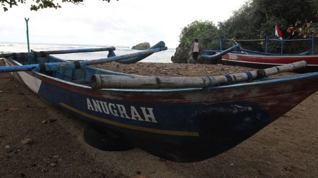 Seorang nelayan membersihkan perahu miliknya di pantai Kondangmerak, Malang, Jawa Timur, Sabtu (24/9/2022).  ANTARA FOTO/Ari Bowo Sucipto